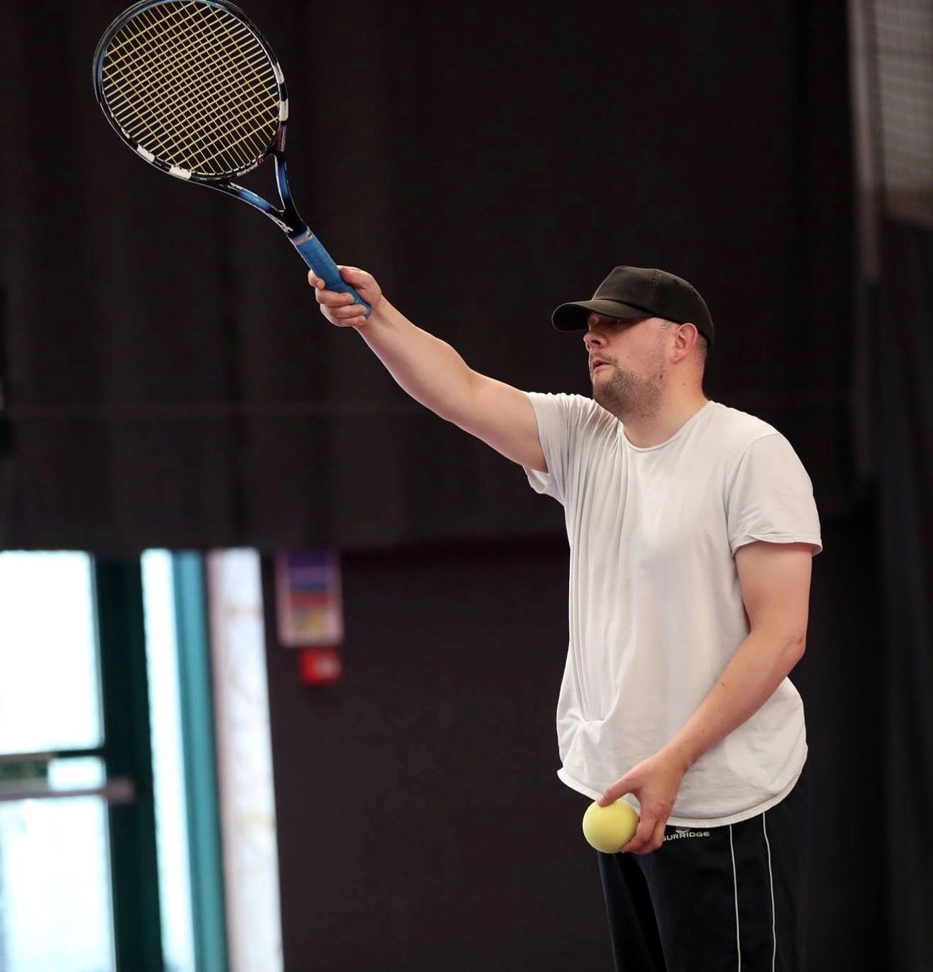 A man playing tennis with a racket and an adapted ball.
